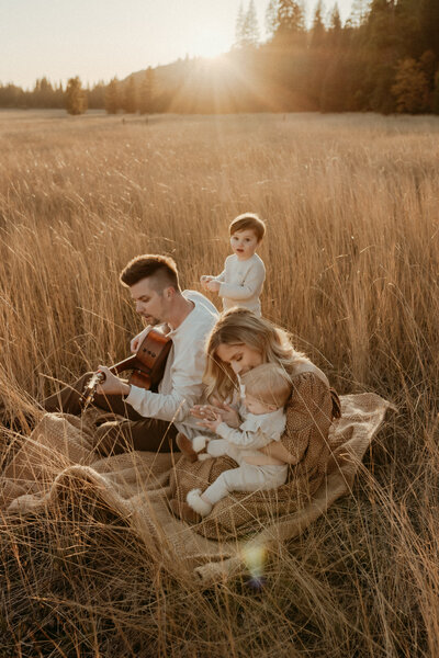 A family playing guitar in a field.