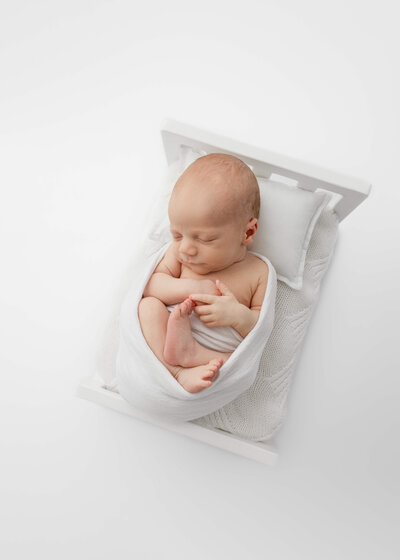 Sleeping Newborn baby wrapped in a natural blanket and swaddled for a studio newborn photography session by Lauren Vanier Photography
