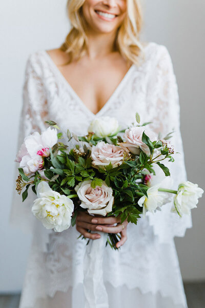 Mariee qui tient un magnifique bouquet de fleurs roses et blanches