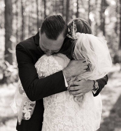 Groom holding bride tightly during first look in woods