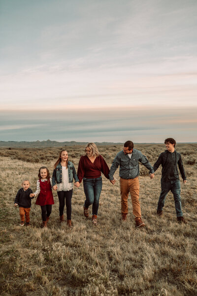 family of six holding hands skipping in a field