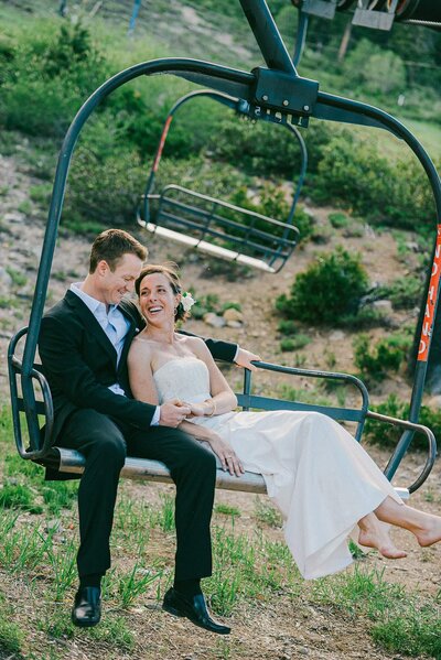 Summer wedding at West Shore Lake Tahoe image of  a couple sitting in a chairlift looking at each other laughing enjoying the moment after just getting married on the Lake
