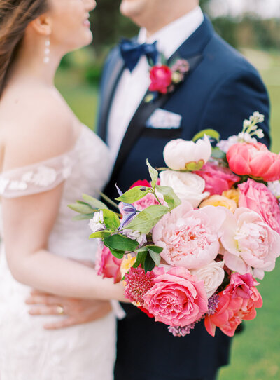 A pink and green wedding bouquet, held by a bride.