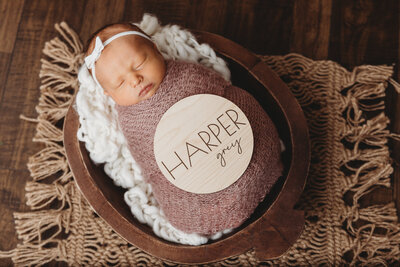 A newborn baby with a wooden sign with their name on it.