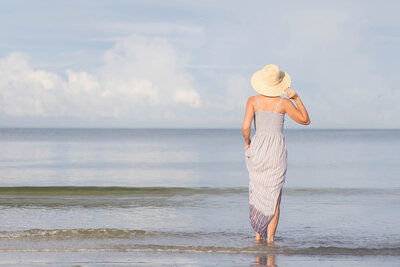 Woman wearing a sun hat walking into the ocean