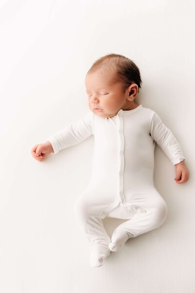 newborn in white sleeper