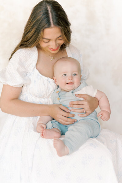 Mom holding baby in front of photo gallery for Richmond Newborn Photography session.