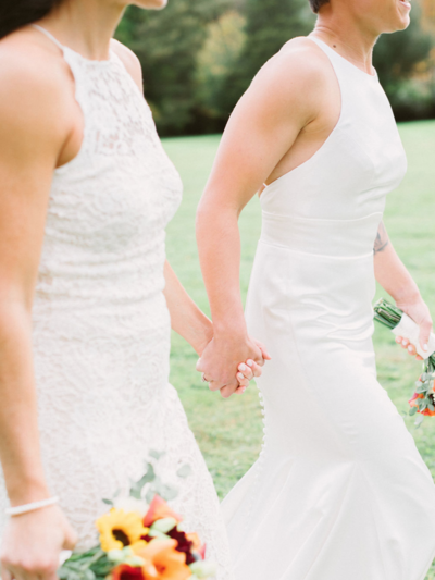 Brides holding hands in backyard wedding in Massachusetts