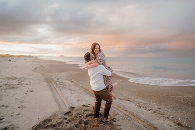 A couple dancing on the beach during their engagement photoshoot at a white sand beach with tashina Narelle, a Waikato and Bay of Plenty Wedding Photographer