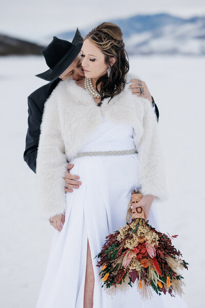 Groom kisses bride's shoulder in Breckenridge winter elopement.