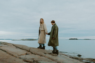 Aikuiset siskot kävelevät käsi kädessä rantakallioilla Helsingin Kallahdessa.