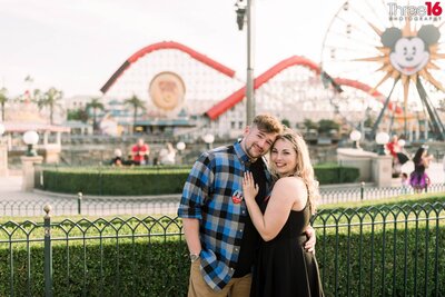 Engaged couple cuddle up as they pose for engagement photos in front of the Anaheim Packing House