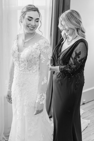 A mom helping her daughter get ready during her wedding enjoying their Raleigh wedding photography by JoLynn Photography