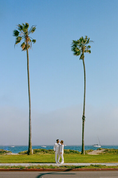 Image from across the street of a wedding couple standing on a sidewalk.
