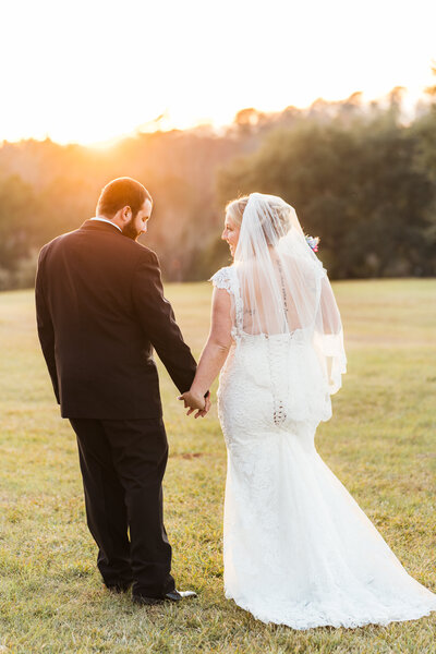 Bride & Groom holding hands in a tree lined open field at Barn at Acorn Ridge in Toomsboro, GA. Savannah, GA weddings.