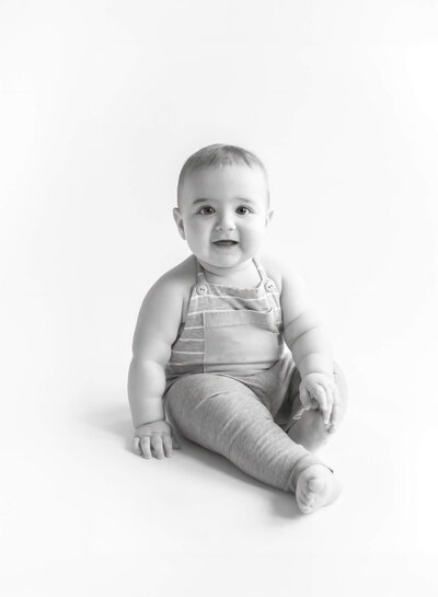 light and airy black and white portrait of sitting baby smiling