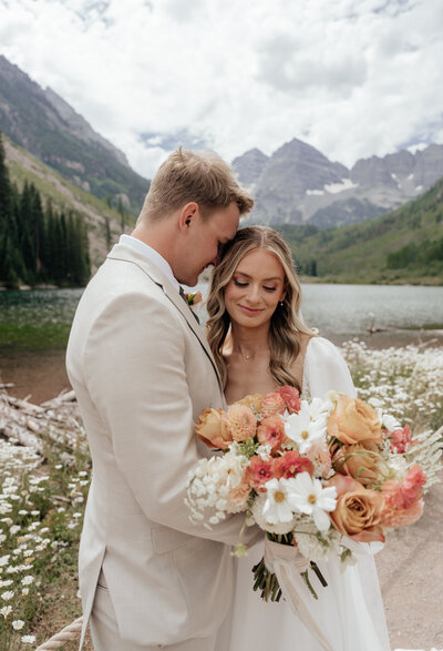 A wedding couple embraces in front of Maroon Bells in Aspen, Colorado.