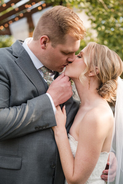 Wedding Photographer, a freshly married husband and wife kiss on their wedding day outside