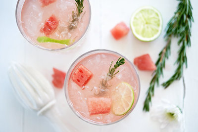 Specialty cocktails garnished with watermelon, rosemary, & lime