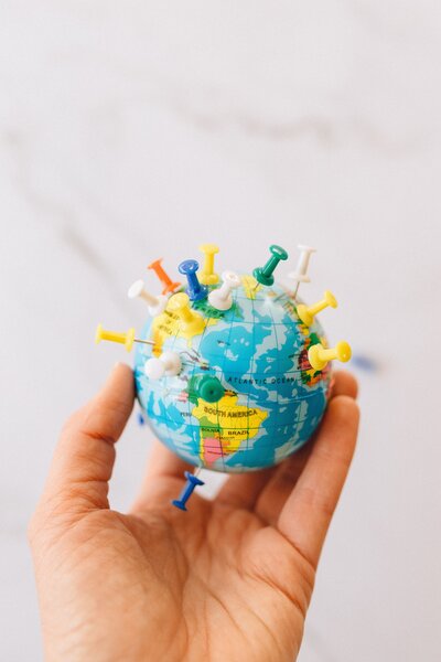 Hand holding small globe with push pins in it