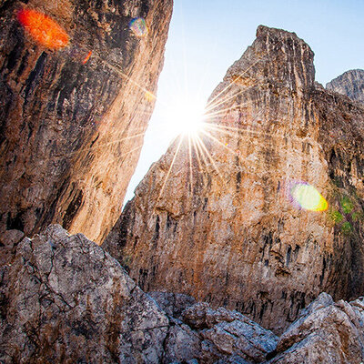 sun shining into a canyon from behind a rock wall