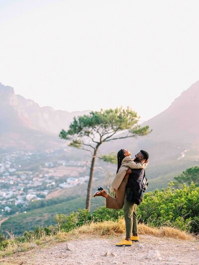 A black couple embraces on Table Mountain in Capetown South Africa, captured by destination wedding photographer Audria Abney