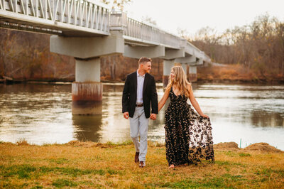 photo of girl and man walking in front of a river