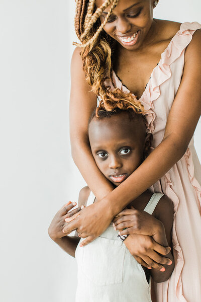 Black mom hugs her shy son in gentle embrace for mother and son photograph