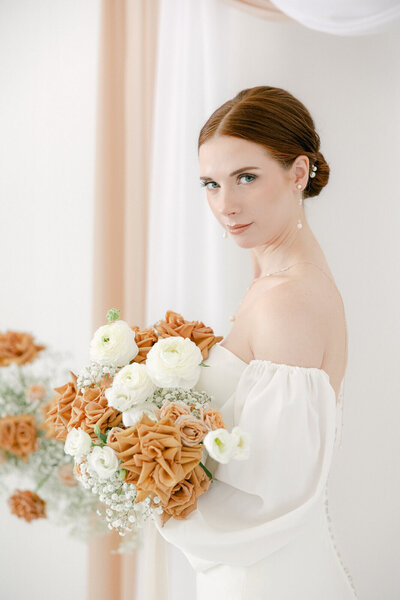 A radiant bride, dressed in her stunning wedding gown, holds a bouquet of exquisite white flowers.