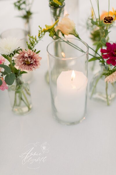 Picture of candle with flowers in vases around it - UME (New England Wedding Planner) were wedding vendors