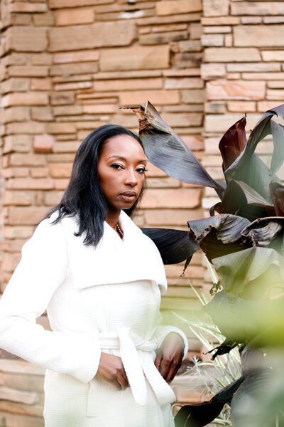 Modern brand shoot with  woman in white coat behind plants