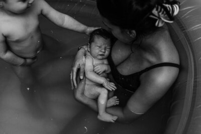 A newborn baby cradled in mummas arms as they sit in the birth pool. Experienced in capturing the beauty and emotion of childbirth. With a keen eye for detail and a passion for telling your birth story.