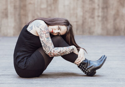 woman with tattoos sitting on the ground looking at the camera