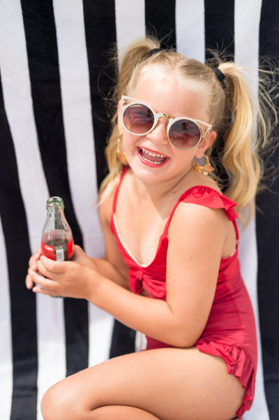 Child in a red swimsuit holding a can of coke