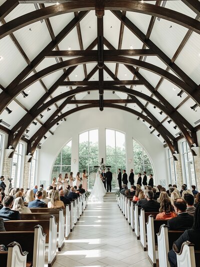 A splendid Texas wedding ceremony in a charming church adorned with authentic wooden beams, beautifully captured by a skilled videographer.