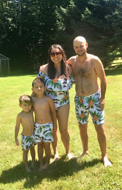 A family of four in tropical swimsuits on a lawn.