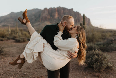 Man holds his soon to be bride while they kiss during their engagement session