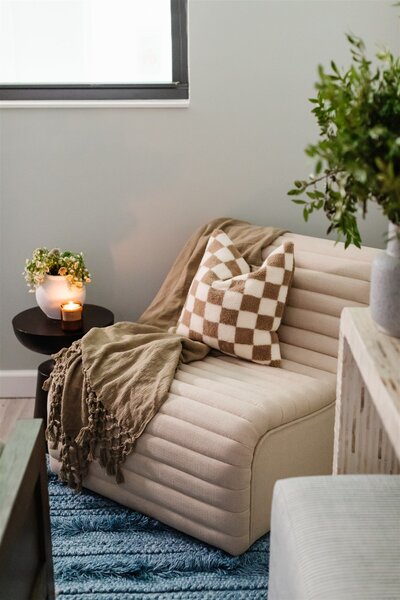 Beige chair with brown checkered decorative pillow