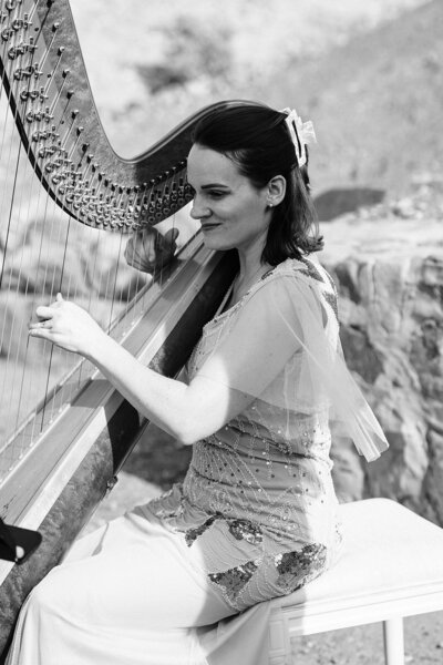 Black and white photo of a harpist at a Death Valley wedding ceremony
