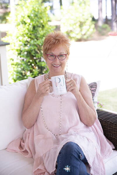 Jane Shine sitting on a porch enjoying a cup of coffee