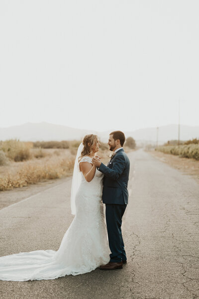 bride and groom standing on the road holding hands