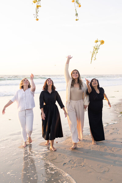 Women on the beach throwing flowers at sunset