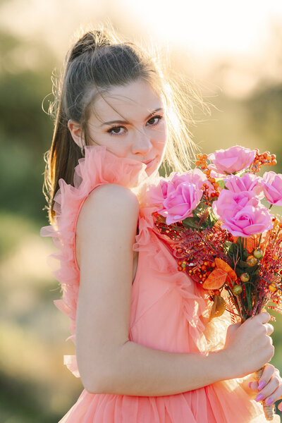 High School Senior in peach tulle sun dress holding flowers