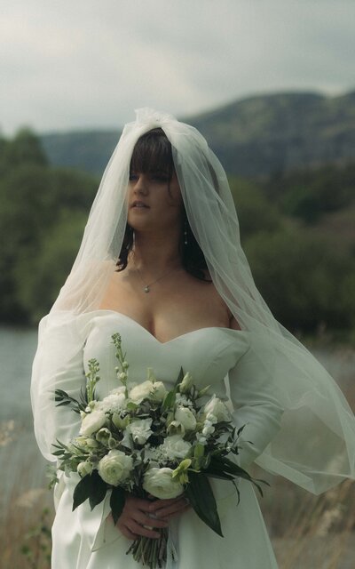Bride holding her bouquet, radiating elegance and joy, captured in a serene moment that highlights her beauty and anticipation on her wedding day