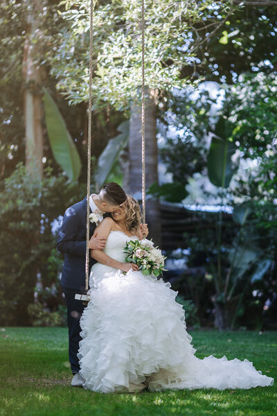bride and bride  kissing on swing