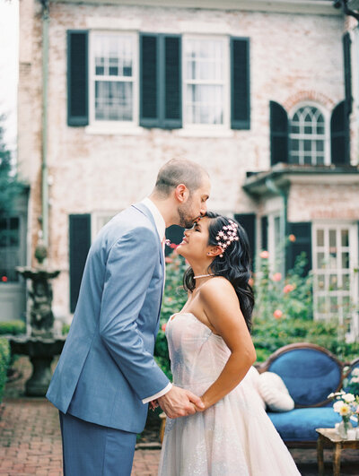 bride and groom kissing in front of stunning wedding venue