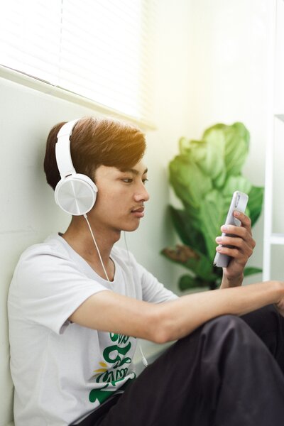 Young man using headphones and smartphone for self-regulation, engaging with a free nervous system support guide