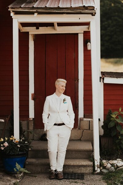 Bride standing in suit in front of red door, Berkshire Farm Wedding