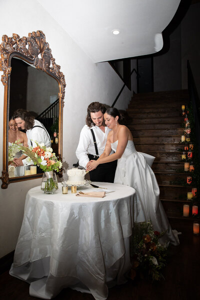 An Austin-based wedding photographer captures the moment of a bride and groom cutting a cake.