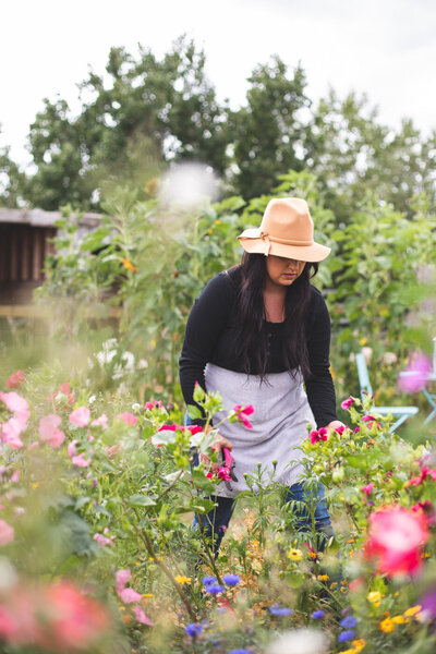 girl in a hat surrounded by pink flowers